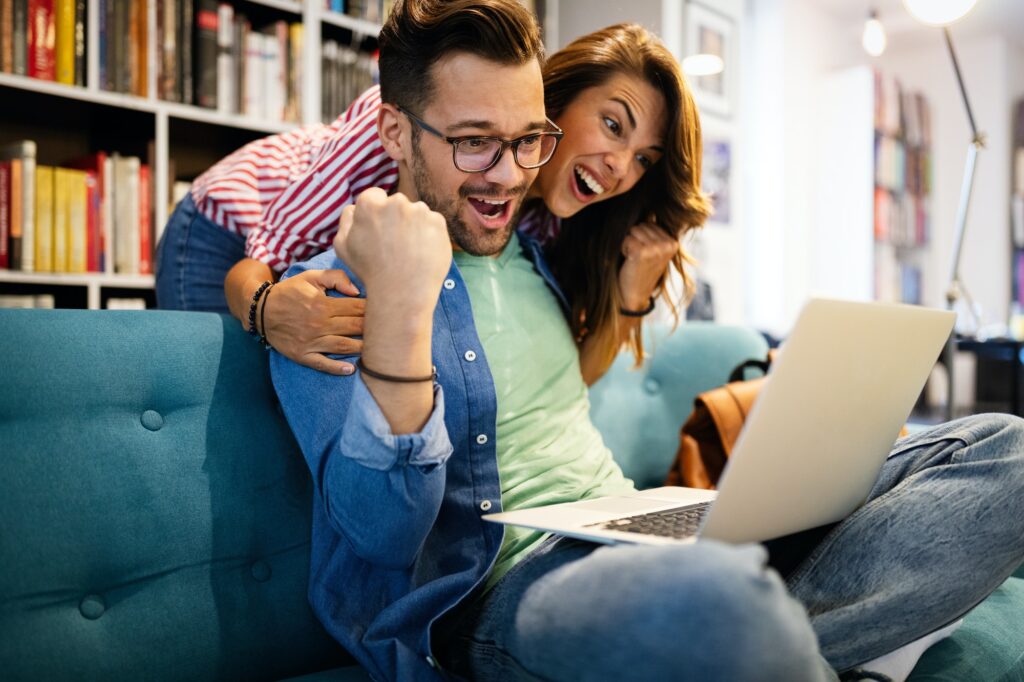 Surprised happy young couple looking at laptop